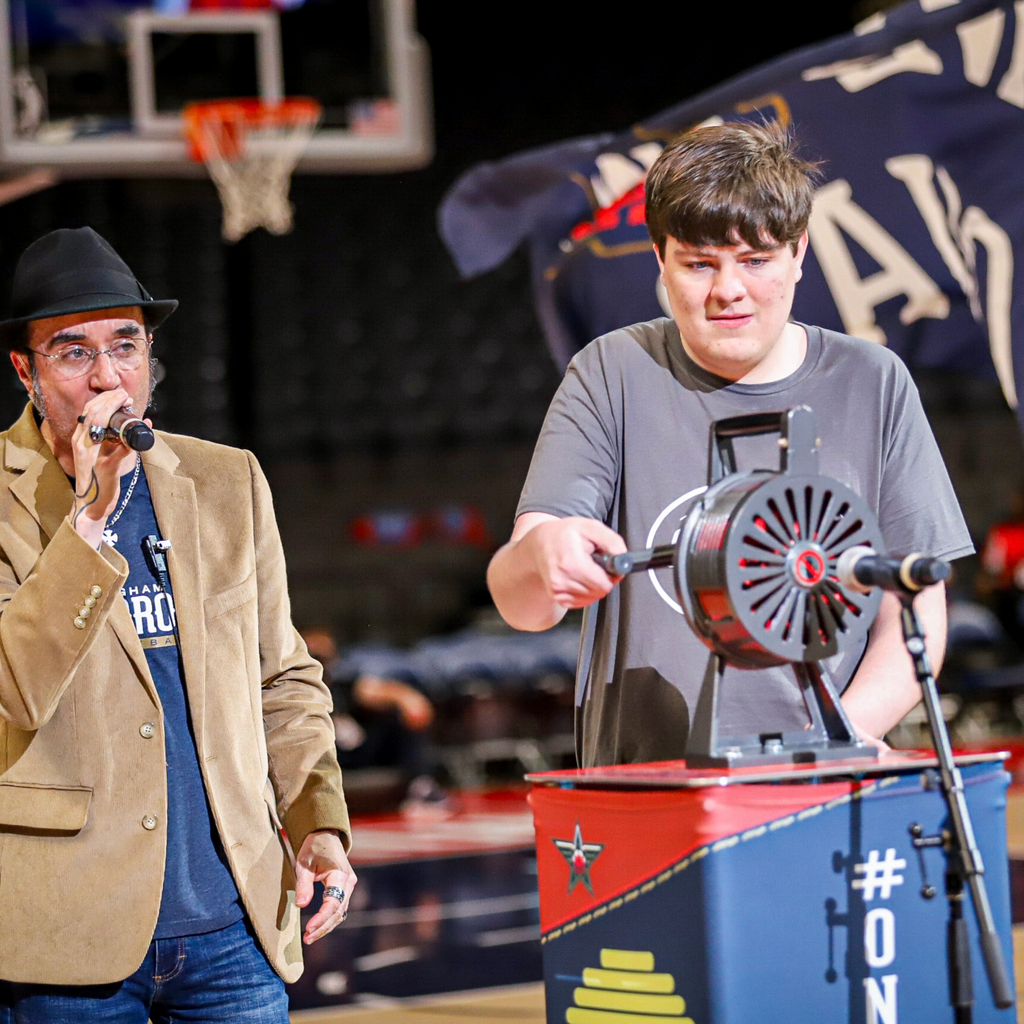 Fan cranking the game day siren on a PropBox custom podium during a live basketball event