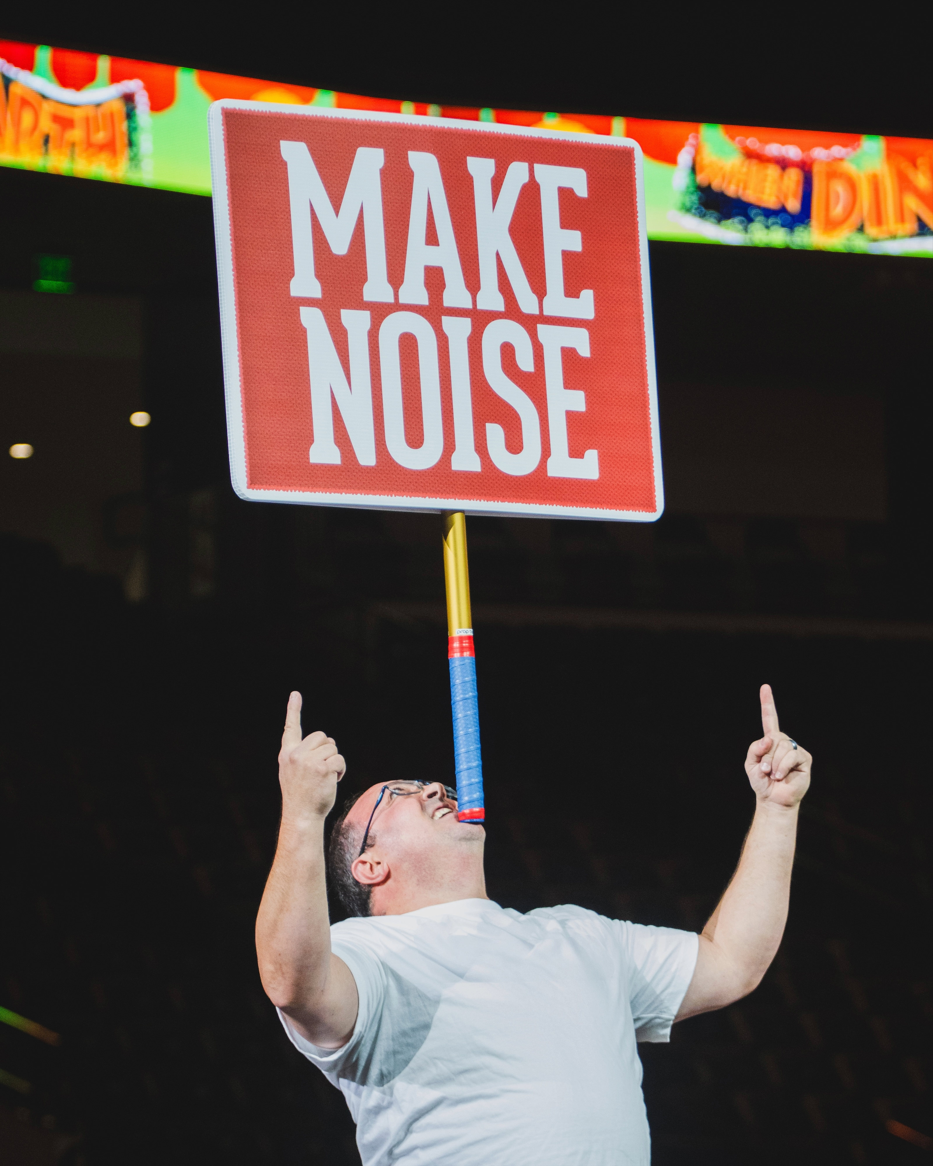 Fan holding oversized Make Noise crowd sign at stadium event